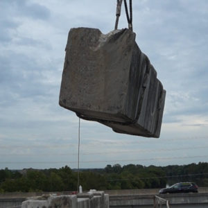 Large piece of concrete lifted by crane from bridge that was cut using wire saw. Texas Cutting and Coring.